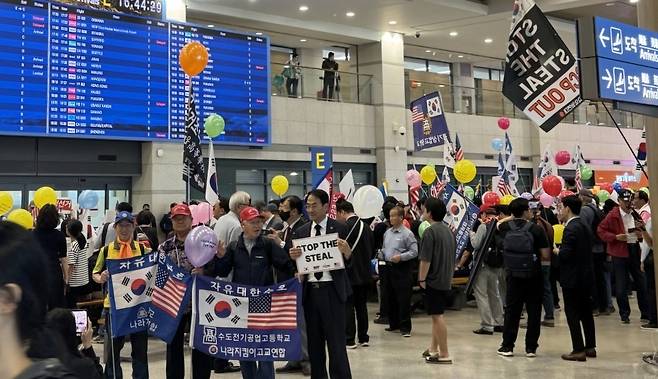 ▲인천공항 제1여객터미널 E환영홀에 몰려든 보수단체 회원들이 태극기와 성조기, 풍선, 피켓을 들고있다. /사진=독자제공