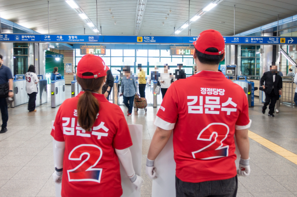 국민의힘 20대 선거운동원인 이은주(왼쪽)씨와 장세민씨가 21일 서울 구로구 개봉역에서 시민들을 향해 인사하고 있다.