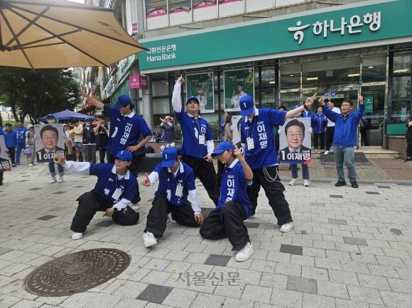 더불어민주당 2030 청년 선거운동원인 시너지유세단이 21일 경기 광명시의 한 인도에서 ‘기호 1번’ 손동작을 취하며 선거유세 무대를 하고 있다. 박상연 기자