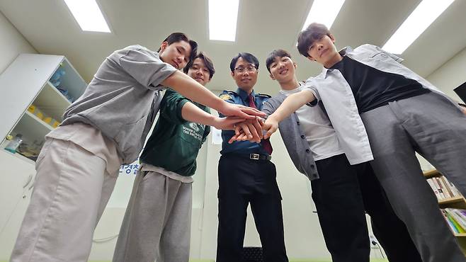 지난 22일 오후 서울 동작청소년경찰학교에서 교장 이백형 경감(가운데)과 학교폭력 예방 교육을 위해 찾은 학생들이 손을 모은 채 파이팅 포즈를 취하고 있다. 전국 56개소에 설치된 '청소년경찰학교'에서는 관내 청소년을 대상으로 학교폭력 예방 교육·경찰 진로 체험 등을 실시한다./안태민 기자