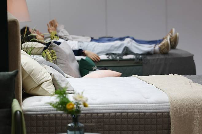 지난 1일 서울 강남구 코엑스에서 열린 2025 서울국제가구 및 인테리어산업대전(소펀앤라이프쇼)에서 관람객들이 전시된 침대에 누워보고 있다./연합뉴스