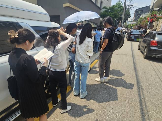 29일 오후 1시20분쯤 한 유권자가 책을 읽으며 투표 차례를 기다리고 있다. 앞에는 시민들이 양산을 쓰며 더위를 피하고 있다./사진=박상혁 기자.