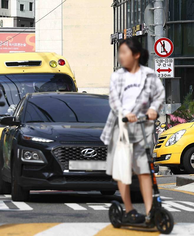 서울 서초구 반포 학원 밀집지역에 이달 13일 킥보드 운행 제한을 알리는 표지판이 설치돼 있다. 그 앞으로 한 학생이 킥보드를 타고 지나가고 있다. 서울=뉴시스