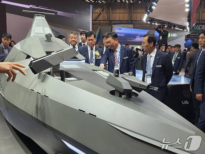 신익현 LIG넥스원 대표이사(사진 오른쪽)와 석종건 방위사업청장(코사지 착용), 신용화 LIG넥스원 미래전장사업본부장이 28일 부산 벡스코에서 개막한 제14회 국제해양방위산업전(MADEX·마덱스)에서 전투용 무인수상정 '해검-X'를 둘러보고 있다(LIG넥스원 제공). 2025.05.28.