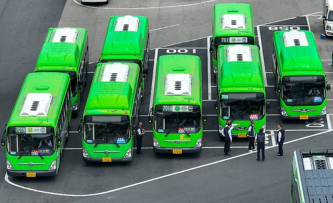 지난 28일 서울 시내의 한 공영버스 차고지에 운전기사들이 버스 앞에서 이야기를 나누고 있다. 연합뉴스