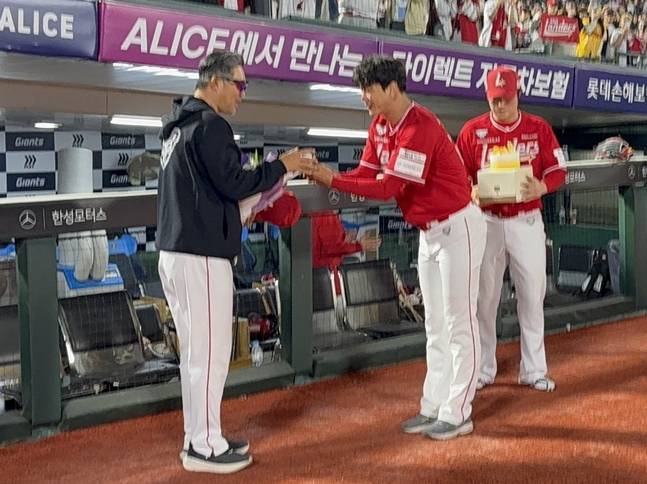 SSG 감독으로 100번쨰 승리를 수확한 이숭용 감독(왼쪽)에게 김광현이 기념구와 최정이 케이크를 선물하고 있다. /사진=SSG 랜더스
