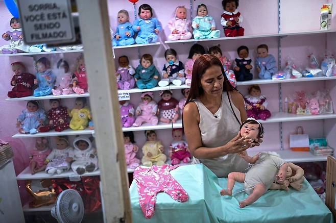 지난달 16일 브라질 리우데자네이루에 위치한 매장에서 상점 주인이 아기 인형의 머리를 조립하고 있다. /AFP 연합뉴스