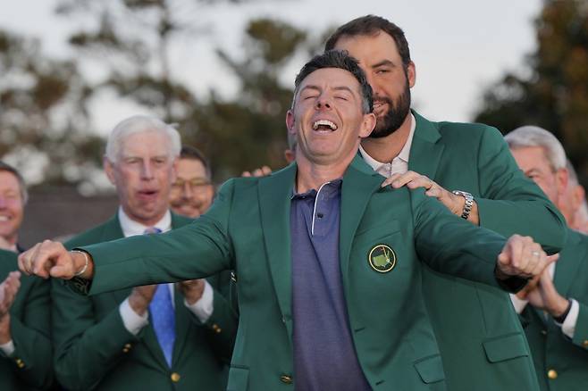 로리 매킬로이(앞)가 4월 열린 마스터스 토너먼트에서 커리어 그랜드슬램을 달성한 뒤 지난해 우승자 스코티 셰플러의 도움을 받아 그린 재킷을 입고 있다. 둘은 올 시즌 나란히 3승씩을 거두고 있다. AP뉴시스