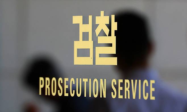 서울 서초구 서울중앙지검 검찰 로고에 직원들의 모습이 비치고 있다. 연합뉴스