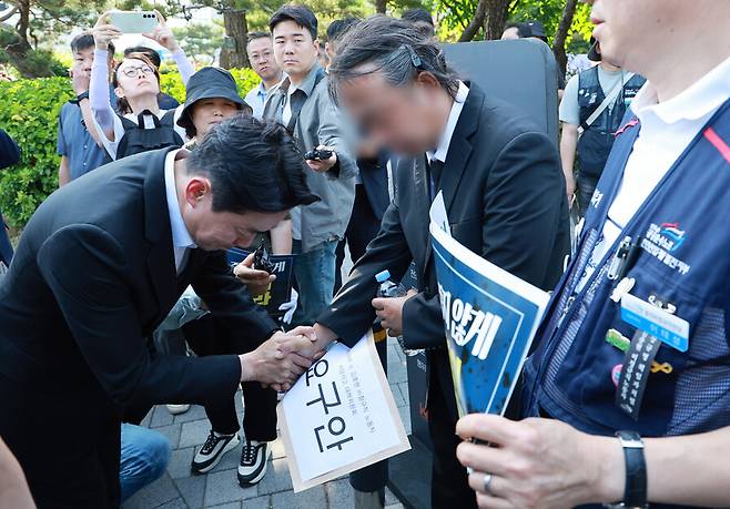 강훈식 대통령비서실장이 6일 서울 용산 대통령실 청사 인근 전쟁기념관 앞에서 태안화력발전소 사고 희생자 고(故) 김충현씨와 관련해 엄길용 공공운수노조 위원장으로부터 요구안 서한을 직접 전달받은 뒤 김씨의 유족을 만나 위로하고 있다. 연합뉴스