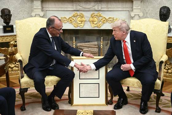 프리드리히 메르츠 독일 총리(왼쪽)가 5일(현지시간) 미국 워싱턴 백악관에서 도널드 트럼프 미국 대통령에게 1869년 독일에서 태어난 트럼프 대통령의 할아버지 프레데릭 트럼프의 출생증명서를 담은 금박 액자를 선물로 주고 있다. AFP=연합뉴스