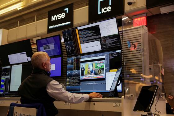 뉴욕 증시의 한 딜러가 도널드 트럼프 미국 대통령과 일론 머스크 테슬라 CEO에 대한 소식을 전하는 화면을 주시하고 있다. 로이터=연합뉴스, 무단 전재-재배포, AI 학습 및 활용 금지〉