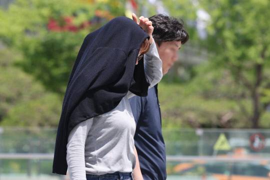 초여름 날씨를 보인 5일 서울 종로구 광화문광장에 한 시민이 외투를 머리에 뒤집어쓴 채 더위를 피하고 있다. 연합뉴스