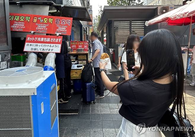유명 호떡 인증샷 남겨야지 (서울=연합뉴스) 김유진 인턴기자 = 지난달 29일 오후 서울 중구 남대문시장의 한 호떡 노점 앞에서 호떡을 산 한 손님이 인증샷을 남기고 있다. 2025.6.8