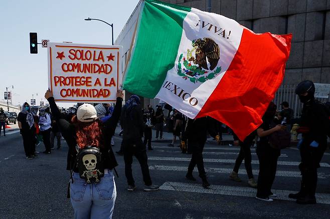 8일 미국 LA에서 열린 이민단속 반대 시위에 참여한 참가자가 '오직 공동체만이 공동체를 보호할 수 있다'고 쓰인 표지판을 들고 행진하고 있다. /연합뉴스
