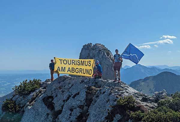 환경단체 회원들이 캄펜반드산 정상에 올라 '벼랑 끝에 걸린 관광'이라고 쓰인 현수막을 펼치며 시위하고 있다. 사진 독일 마운틴 윌더니스.