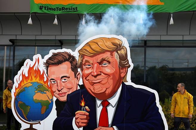 그린피스 활동가들이 11일(현지시각) 체코 프라하에 위치한 테슬라 매장 앞에서 도널드 트럼프 미국 대통령과 일론 머스크 테슬라 최고경영자가 지구에 불을 지르는 모습으로 풍자한 팻말을 세우고 시위를 하고 있다. 사진 로이터 연합뉴스