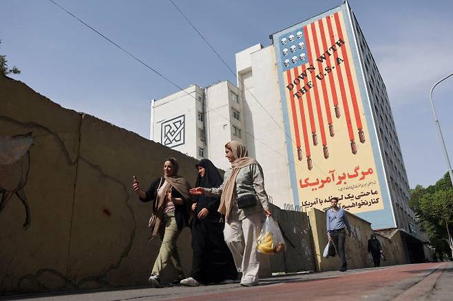 이란 여성들이 4월 26일(현지시간) 이란 테헤란의 거리에서 반미 벽화를 지나가고 있다.(사진=로이터)