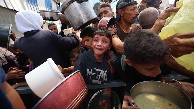 지난 11일(현지 시각) 가자지구 중앙 누세이라트의 배급소에서 팔레스타인 한 어린이가 식량 배급을 기다리며 울먹이고 있다./AFP 연합뉴스