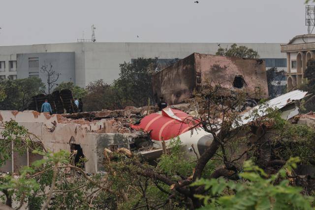 인도 당국 관계자들이 13일 인도 서부 구자라트주 아마다바드의 사르다르 발라바이 파텔 국제공항 근처에서 추락한 에어인디아 여객기 사고 현장을 점검하고 있다. 아마다바드=EPA 연합뉴스