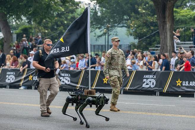 14일(현지시간) 미국 워싱턴 D.C.에서 열린 군사 퍼레이드에서 군인과 로봇개가 행진을 하고 있다. 사진=XINHUA