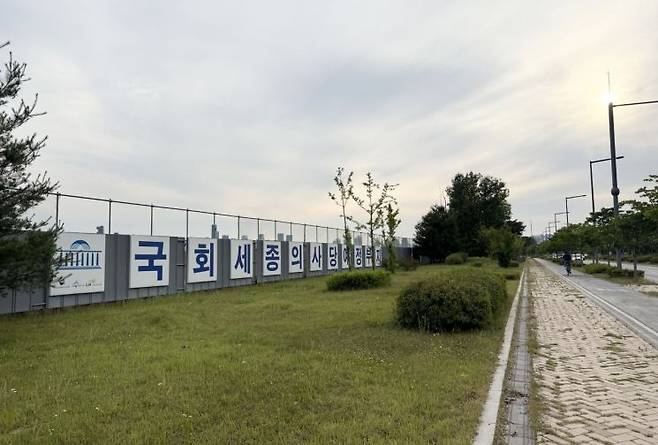 세종특별자치시 세종동 국가상징구역 일대에 조성된 국회세종의사당 부지 모습. 길게 뻗은 도로를 따라 회색 벽이 길게 설치돼 있다. 자전거를 타고 이동하는 몇몇 사람 외에는 인적이 드물어 휑한 분위기를 자아낸다. 김평화 기자