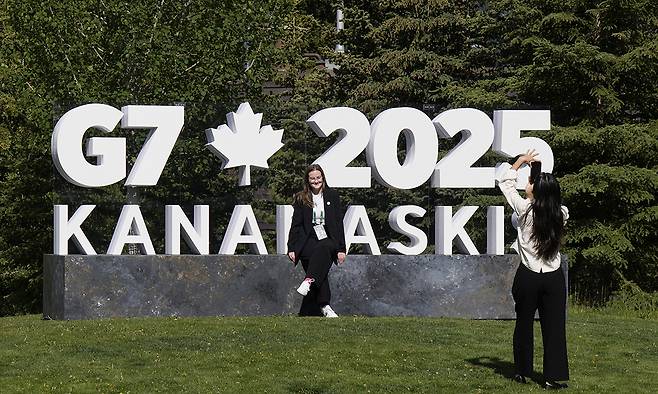 15일(현지시간) G7 정상회의가 열리는 캐나다 앨버타주 카나나스키스에 설치된 관련 조형물 앞에서 관광객들이 기념 촬영을 하고 있다. AP연합뉴스