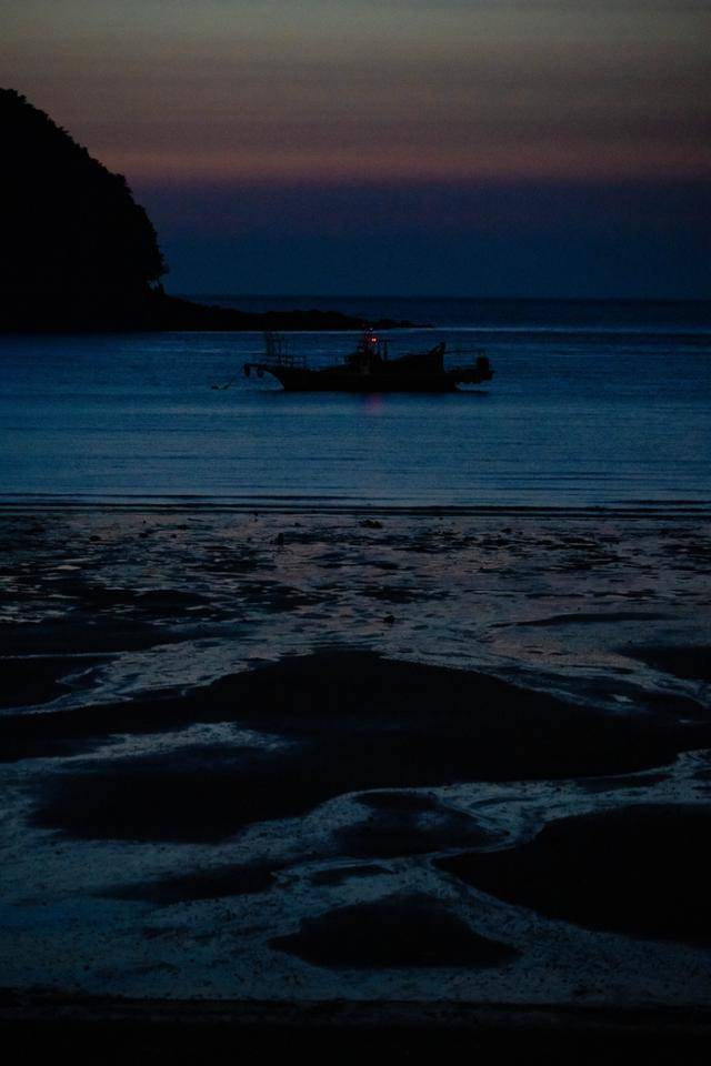 밤이 내린 대이작도의 갯벌 뒤로 작은 어선이 떠 있다.