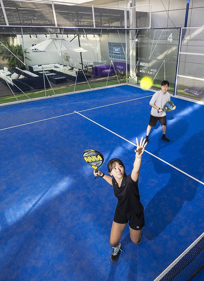 A woman attempts a smash at the padel court in I’Park Mall, Yongsan, Seoul. The transparent glass walls surrounding the court allow for a wider variety of plays than traditional tennis. /Yang Soo-yeol
