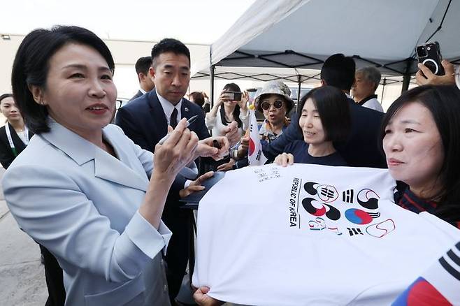 G7 정상회의에 참석하는 이재명 대통령과 함께 캐나다를 방문한 김혜경 여사가 17일(현지시간) 캘거리 한인회관에서 환영나온 주민들의 요청에 티셔츠에 서명하고 있다. ⓒ연합뉴스