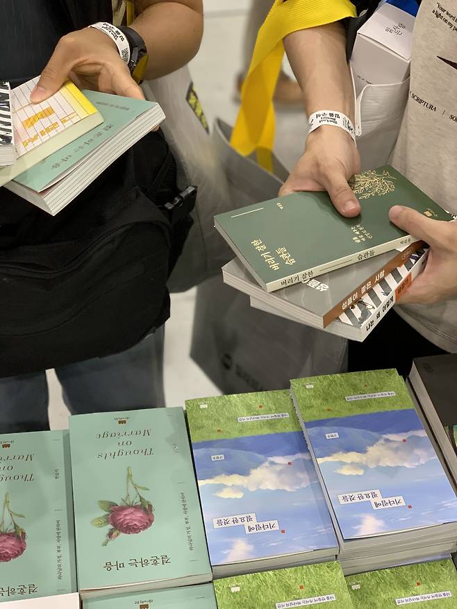 2025 서울국제도서전의 기독교 책마을 부스를 찾은 뒤 책을 구매한 관람객들. 구름이머무는동안 제공