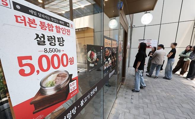 지난 13일 할인 안내문이 붙은 서울 시내 한 인생설렁탕 매장에서 시민들이 줄을 서고 있다. 연합뉴스