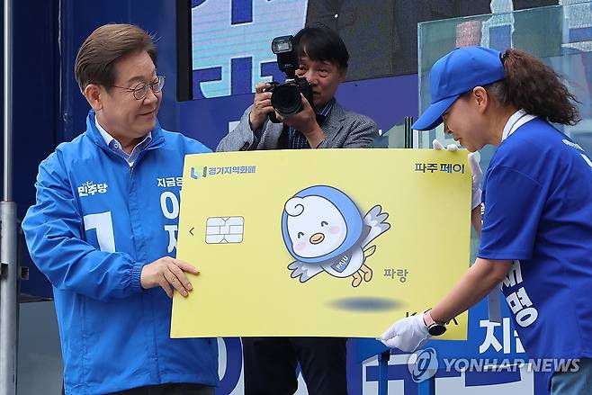 지역화폐 모형 전달받는 이재명 후보 (파주=연합뉴스) 김주성 기자 = 더불어민주당 이재명 대선 후보가 20일 경기 파주시 금릉역 중앙광장에서 열린 유세에서 지역화폐 모형을 전달받고 있다. 2025.5.20 utzza@yna.co.kr