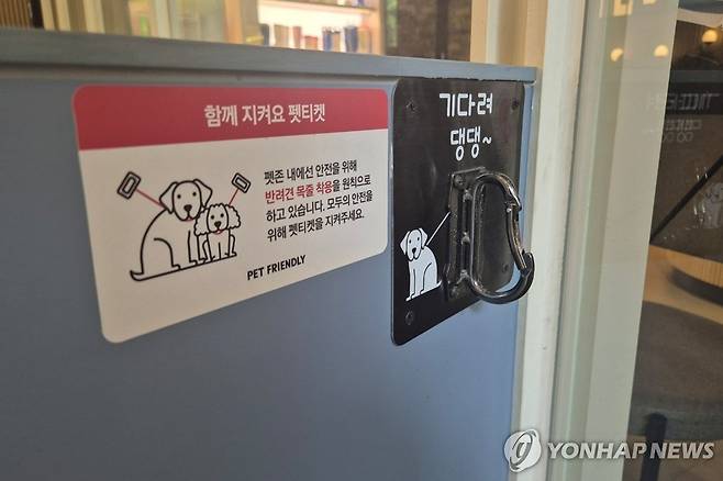 "기다려 댕댕" (서울=연합뉴스) 이승연 기자 = 지난 19일 서울 마포구 경의선숲길에 위치한 할리스커피의 펫 프렌들리 매장에 붙어있는 '목줄 착용' 안내문. 2025.6.21 winkite@yna.co.kr