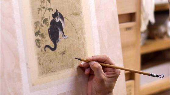 '추일한묘'의 벌레 먹어 훼손된 비단을 메우고 색맞춤을 진행중인 모습. 사진 간송미술문화재단