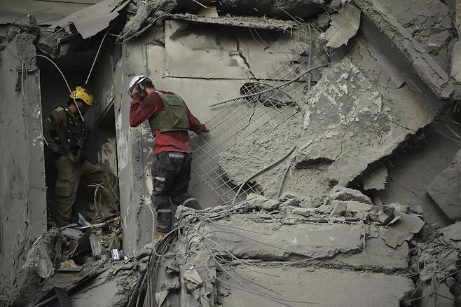 24일(현지시간) 이스라엘 남부 베르셰바에서 이스라엘 구조대가 이란의 미사일 공격으로 파괴된 주거 건물 잔해를 수색하고 있다. AP/뉴시스
