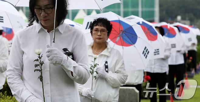 25일 오전 부산 남구 유엔기념공원에서 열린 제75주년 6·25전쟁 참전 유엔전몰용사 추모제에서 태극기 우산을 쓴 참석자들이 유엔군 전몰장병 묘역을 참배하고 있다. 2025.6.25/뉴스1 ⓒ News1 윤일지 기자
