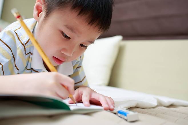 A boy writing with a pencil (123rf)
