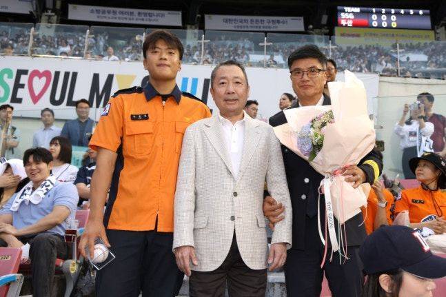 두산 베어스 구단주인 박정원(가운데) 두산그룹 회장이 24일 잠실 SSG전 도중 손용복 소방교(왼쪽)와 손정복 소방경과 기념사진을 찍고 있다. ⓒ두산 베어스