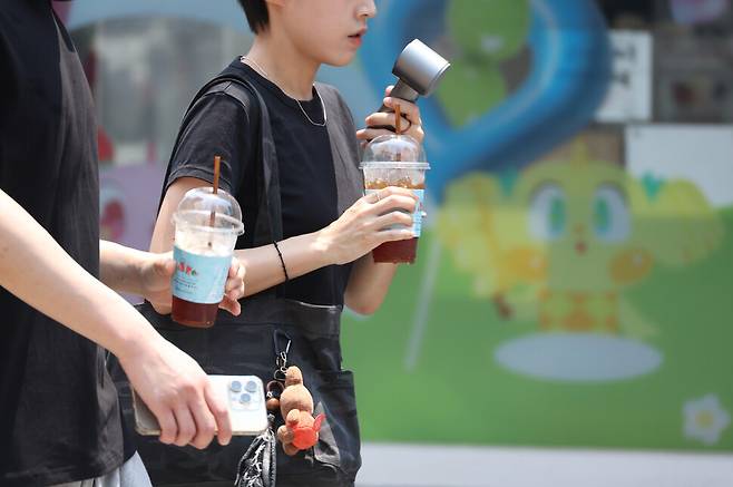 지난 28일 대구에 폭염경보(군위 제외)가 내려진 가운데 중구 동성로에서 시민들이 아이스 아메리카노와 휴대용 선풍기로 더위를 식히며 이동하고 있다. 연합뉴스