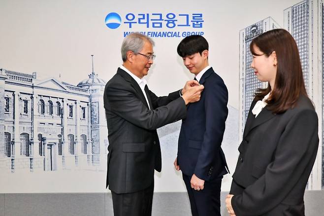 임종룡 우리금융그룹 회장이 그룹의 새 가족이 된 동양생명·ABL생명 직원에게 디지털 선도의 의미가 담긴 새로운 그룹 보조휘장을 달아주고 있다. 우리금융 제공