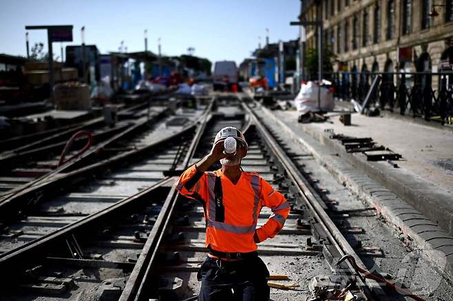 1일(현지시간) 프랑스 남서부 보르도의 트램 노선 건설 현장에서 한 노동자가 더위를 식히기 위해 물을 마시고 있다. ⓒ AFP=뉴스1