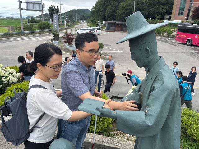 시각장애인 김기화(왼쪽 두 번째) 대구하늘빛교회 목사가 30일 인천 강화교산교회 앞에 설치된 선상세례 동상을 만지고 있다.