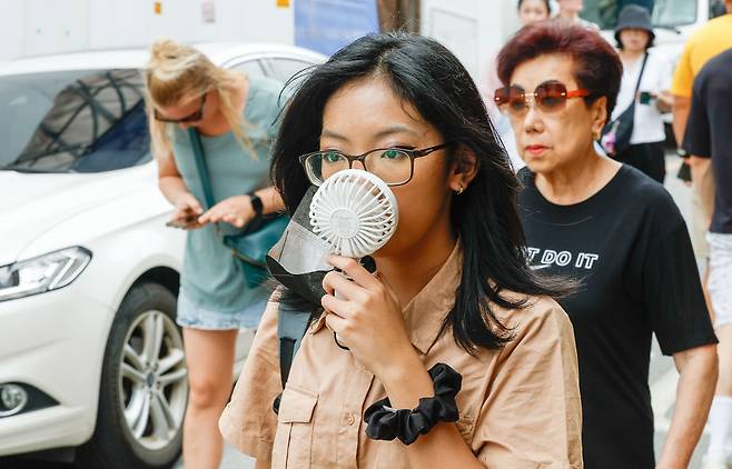 서울 최고온도 33도까지 올라 습하고 더운 날씨를 보인 2일 서울 종로구 북촌한옥마을에서 한 외국인 관광객이 손선풍기로 더위를 피하고 있다.