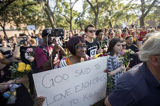 인종 차별에 반대하는 시위대가 2015년 6월 미국 사우스캐롤라이나 찰스턴의 흑인 교회서 백인우월주의 청년이 저지른 총기 난사 사건을 애도하며 행진하고 있다. 한 참가자의 팻말에 “하나님은 서로 사랑하라고 말씀하셨다”고 적혀있다. AP뉴시스