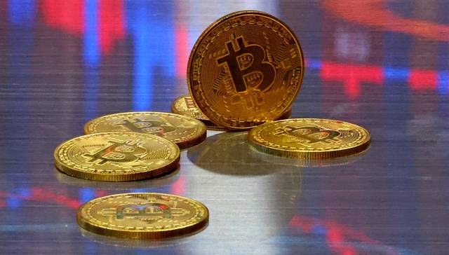 비트코인 모형이 놓인 바닥에 코인 시세 그래프가 비치는 모습. 연합뉴스