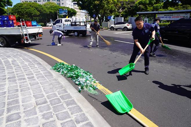 7일 신제주로터리 도로 위로 쏟아진 소주병과 상자를 치우는 도청 청원경찰들.