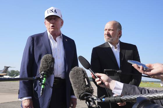 도널드 트럼프 미국 대통령이 6일(현지시간) 뉴저지주에서 워싱턴으로 돌아오는 대통령 전용기(에어포스원)에 탑승하기 전 공항에서 취재진과 만나 이야기하고 있다. 오른쪽은 하워드 러트닉 상무장관. 〈사진=AP/연합뉴스〉