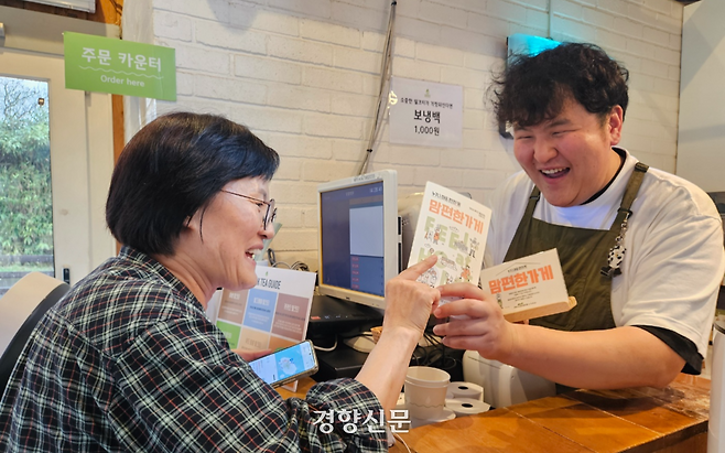 행복하게 사회적협동조합이 제주시 애월에 있는 한 카페에 맘편한 가게를 인증하는 안내판을 전달하고 있다. 행복하게 사회적협동조합