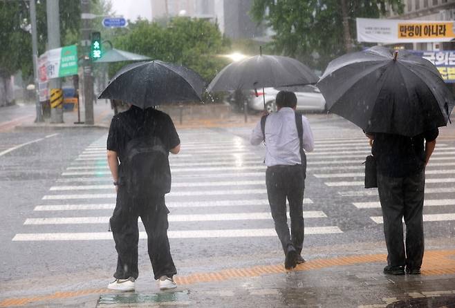 서울 서남권에 호우주의보가 발효된 8일 서울 영등포구 여의도 국회 인근에서 시민들이 우산을 쓰고 있다. 연합뉴스